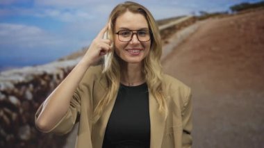 Açık havada gülümseyen bir kadın kafasında parmağıyla düşünceli bir jest yapıyor. Sarı saçlar günlük güneşlik, mavi gökyüzü gözlükleri arka planda doğa ilhamı kavramı.