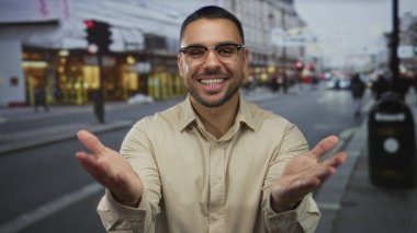 Kalabalık bir şehir sokağında kameraya el hareketleriyle öpücük yollayan bir adam..