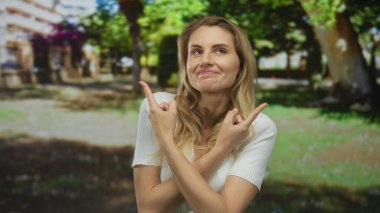 Güneşli bir günde yemyeşil ağaçların altında, iki eliyle parkı gösteren bir kadın düşünceli bir gülümsemeyle dalgınlığını ve karar verme mekanizmasını ifade ediyor..