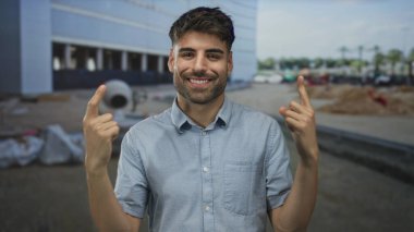 İnsan parmağı, modern cephe tarafından gün ortasında iyimser bir ifadeyle çerçevelenmiş yapıyı işaret ediyor; iyimser bir ilerleme..