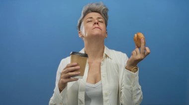 Kadın bir paket kahve fincanı ve jöleli donutı stüdyo ortamında başını yukarı eğerek, dikkatli bir duraksama; keyif.