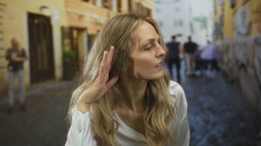 Kadın kapı çalmak için elini kaldırır. Cama genç sarışınlar bakar. Pencere kenarında dikkatle dinlerler..