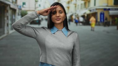 Kadın, hareketli bir sokakta kendine güvenle selamlıyor zarafeti günlük tarzla harmanlıyor şehir cazibesini ve profesyonelliği canlı sokak hayatı zarafetle gözler önüne seriyor..