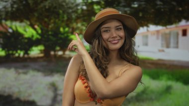 Bikinili kadın parmak gösterirken çıplak omuz gösteriyor; oyuncu özgüven sevinci.