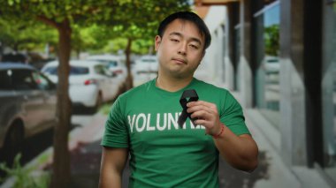 Şehir caddesinde elinde siyah kurdele tutan genç adam, arka planda ağaçlar ve arabalarla gönüllü yas tutarken kasvetli ruh halini gösteriyor..