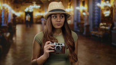Müzede elinde antika bir kamerayla gezen, etrafı sanat ve zarif dekorlarla çevrili genç bir İspanyol kadın, kapalı bir turist deneyimi yaratıyor..