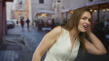 Kadın el ele tutuşup akşam ışığı altında meşgül bir kaldırım taşı caddesinde dinleyerek kargaşa yaratıyor..