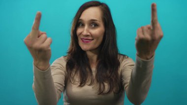 Mavi arka plana karşı kollarını kaldırmış gülümseyen bir kadın küstahlık ve meydan okumayla cesur bir jest ve canlı bir atmosfer vurguluyor..