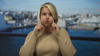 Yanakları şişen ve iskele rıhtımında parlak güneş ışığı altında demirlemiş bir kadın, neşeli bir merak..