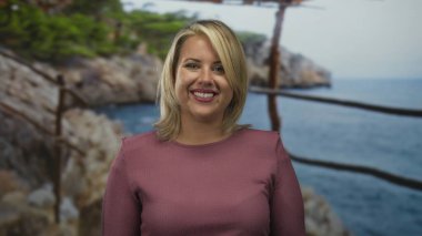 Genç sarışın kadın güneşin altında gülümsüyor ve nazikçe kumlu sahilde ellerini çırpıyor. Huzur, neşe, huzur ve barış..