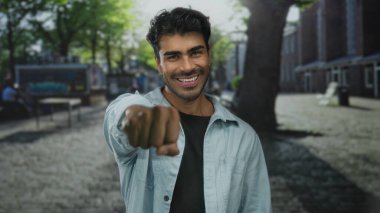 Günlük gömlekli adam, güneşli caddede neşeli yumruk hareketinde kameraya doğru yumruk sallıyor; dayanışma.