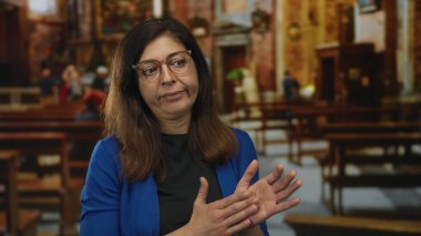 Kilisede el çırpan bir kadın sıra sıra sıralanmış banklar ve süslemelerle kilisede el çırpıyor..