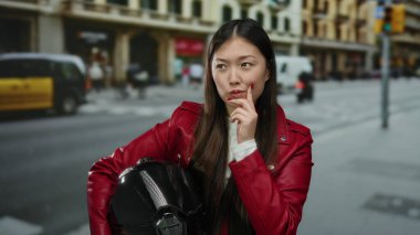 Kırmızı ceketli kadın, canlı bir açık hava sahnesinde şehir hayatı tarzını ve düşünceli ifadesini sergileyen miğfer taşıyan hareketli şehir caddesini düşünüyor..