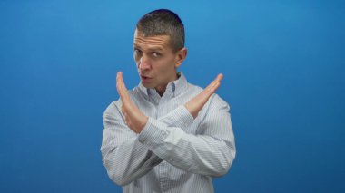 Katı mavi duvara karşı el kol hareketi yapan bir adam, izole bir ortamda reddediyor ya da anlaşmazlığını dile getiriyor, kendine güvenen bir tavır ve mesajın netliği için..