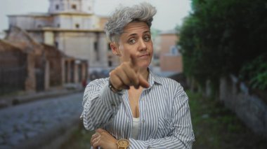 Sokakları gösteren çizgili tişörtlü, gri saçlı bir kadın. Belirsizlik yansıması..