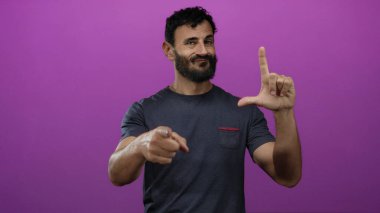 Sakallı İspanyol bir adam canlı pembe bir arka plana karşı ezik bir hareket sergiliyor, anlamlı el hareketleri ve yüz ifadesi ile mizahi alaycılık yapıyor..