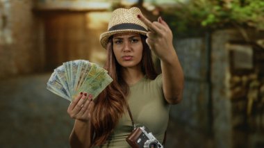 Açık havada elinde Peru parası olan, şapkalı ve kameralı bir kadın şehir ortamında turist hayal kırıklığını gösteriyor..