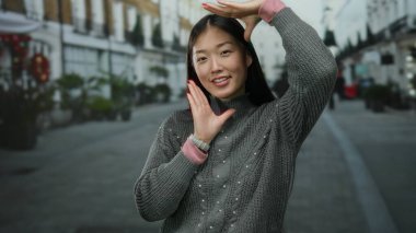 Kadın kentin sokaklarında yaratıcı bir şekilde poz veriyor. Kentin dışında kendini çerçeveleme hareketlerini yakalıyor..