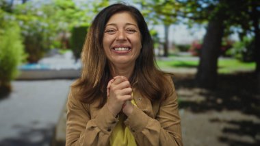 İspanyol kadın güneşli bir öğleden sonra güneşli bir öğleden sonra yeşil parkta yumruklarını sıkar; zafer sevinci.