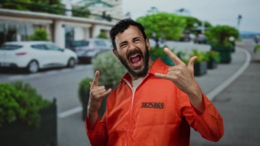 Turuncu hapishane tulumlu İspanyol bir adam sokakta kaya gibi bir jest yapıyor. Mizah ve isyanı üç karede harmanlıyor..