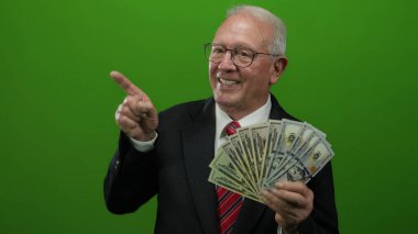 Takım elbiseli kıdemli bir adam bize dolar tutuyor ve canlı yeşil bir arka plana gülümsüyor. Başarıyı ve serveti aktarıyor..