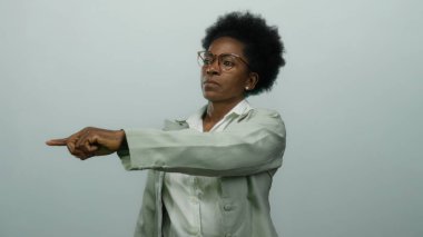 Kadın, izole edilmiş beyaz bir arkaplanda kararlı bir ifadeyle, gözlük ve takım elbise takarak, otoriteyi ve karar verme mekanizmasını profesyonel bir bağlamda vurgulayarak ayrılmak istiyor..