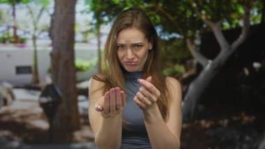 Ciddi genç kadın avuçlarını havada tutuyor ormanda dilencilik yapıyor gün ışığında temizliyor; çaresizlik.