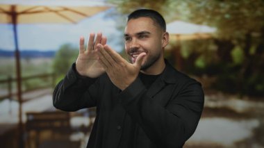 Gülümseyen genç İspanyol adam, para harcayan jestini elleri ile neşeli bir gülümseme ile yapıyor; cömertlik bolluk zenginlik.