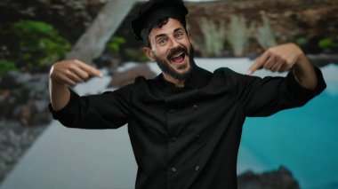 Otelde sakallı İspanyol bir aşçı, bir otelde sırıtıyor, ceketini doğal ve mavi suların arka planına gösteriyordu..