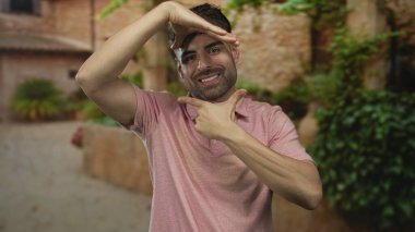 Güneşli eski şehir sokağında taş bina cepheleri ve saksı yeşilliği ile kaplanmış insan çerçeveleri; neşe.