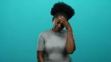 Elleri başlarının üzerinde olan kadın, mavi arka planda stres gösteriyor. Düşünceli bir duruş ve yalnızlığı temsil eden, duygularını ve iç gözlem duygularını aktarıyor..