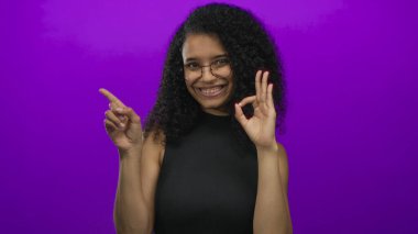 Kadın elini uzatıp işaret dilini mor stüdyo duvarına yaslıyor. Güven onayı..