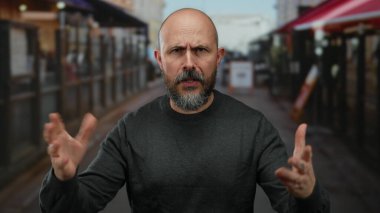 Sakallı kel bir adam şehir arka planında bulanık şehir sokaklarında duygularını ifade ediyor..