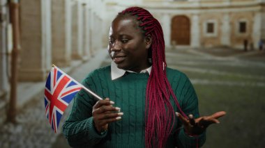 İngiliz bayrağı taşıyan bir kadın açık hava üniversitesinde kültürel çeşitlilik ve eğitim ortamını tarihi bir İngiltere 'de sergiliyor..
