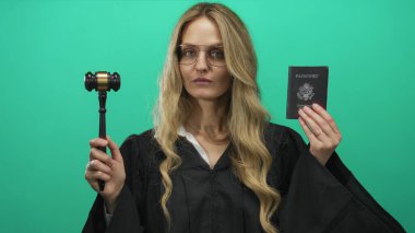 Amerika Birleşik Devletleri pasaportu ve tokmağını taşıyan yargıç üniforması giyen kadın yeşil arka plana karşı, yetki ve kimlik gösterme.