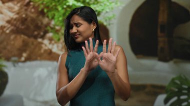 Dışarıdan dışlanmış bir kadın, gün boyunca sokak ortamında elleri havada, canlı kentsel arka planda, tarafsız bir ifadeyle reddediliyor..