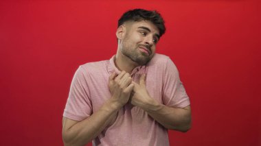 Kırmızı stüdyo ortamında omuz silken adam, şaşkın ifadeyle kaşlarını kaldırdı ve avuçlarını açık bıraktı..