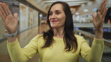 İspanyol kadın, parlak ışıklandırılmış alışveriş merkezinde büyük boy jest göstermek için el ele tutuşuyor..