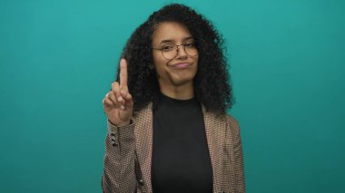 Gözlüklü ve ekose ceketli genç İspanyol kadın yeşil stüdyoda parmak göğse, inkar.