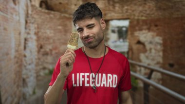 Kırmızı cankurtaran gömlekli adam, Roma harabelerinde fındıkla kaplanmış dondurma tutuyor. Rahatlama düşkünlüğü..