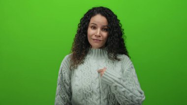Kablolu örgü süveter giyen İspanyol kadın gülümsüyor ve canlı yeşil arka plana başparmak sallayarak olumlu duygular ve onay veriyor..