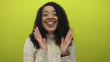 Kablo örgü süveter giyen, gülümseyen ve dişlerini gösteren bir kadın stüdyoda limon yeşili arka planda..