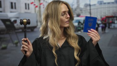 Kadın yargıç elinde Ukrayna pasaportu ve sokak ortamında tokmağı tutarak dışarıda yasal otoriteyi ve kimlik doğrulamasını simgeliyor..