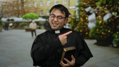 Şehrin dışındaki rahip elinde İncil 'le Noel ağacının çevresini aydınlatıyor.