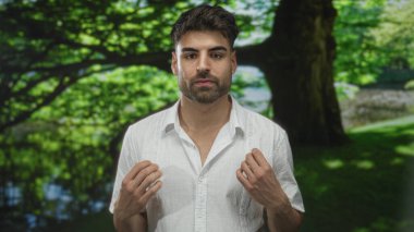 Adam güneşli yeşil parkta yansıtıcı su ile sakin gölet yanında kapalı elleri ile dua; sessiz meditasyon dinginliği.