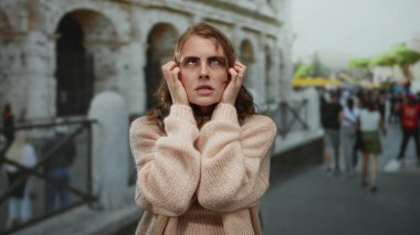 Roma Kolezyumu 'nun dışındaki kadın yoğun şehirde stresli görünüyor. Parlak bir günde kazak giyiyor..