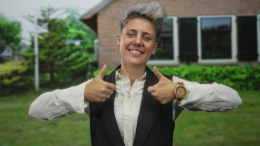 Kısa gri saçlı, siyah yelek giyen bir kadın, tuğla bina girişinde iki kez onay verdi..