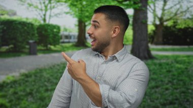 Adam çizgili gömlek giyerken yeşil ağaçlar ve çitlerle caddeleri işaret ediyor; heyecan.