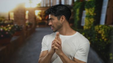 Elleri havada genç İspanyol bir adam yeşil güneşli yeşilliklerin arasında sokakta el tabancası hareketi yapıyor..