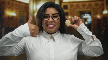 Kilisede elinde kripto para tutan, gülümseyen, gözlük takan, büyük beden, baş parmak yukarı, kapalı, mutlu, genç, dijital para birimi gösteren, Latince.